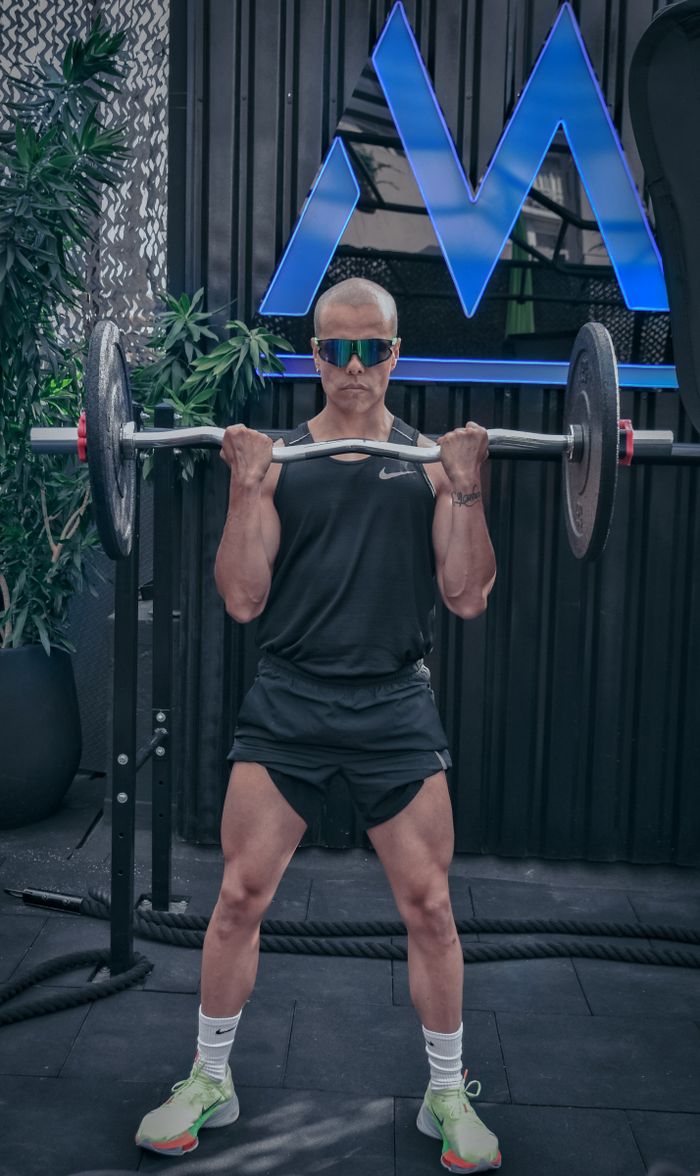A fit man lifting a barbell indoors, showcasing strength and fitness. Perfect for health and fitness themes.